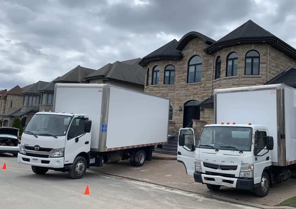 two moving trucks parked in front of a house for a residential moving service