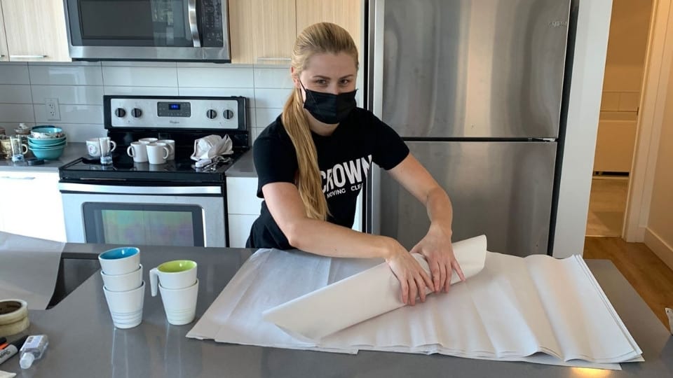 Crown Mover carefully wrapping kitchen items for a secure moving service
