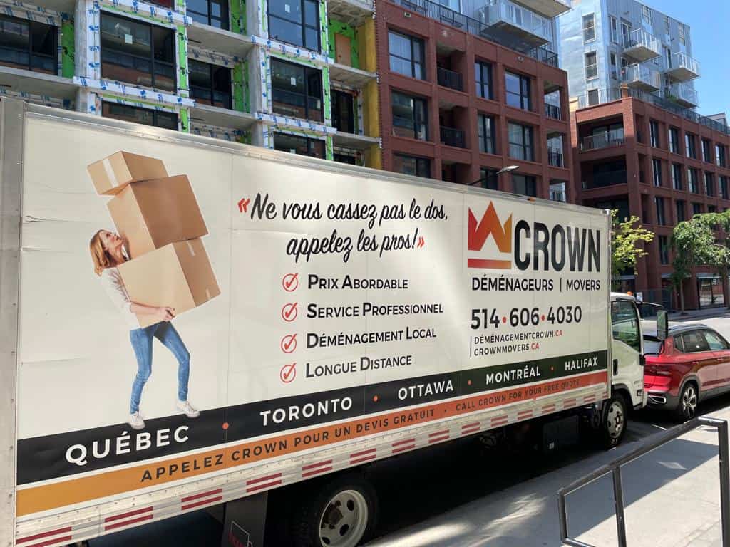 crown movers moving truck in front of a building